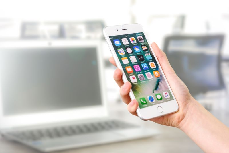 Hand holding a smartphone over a desk